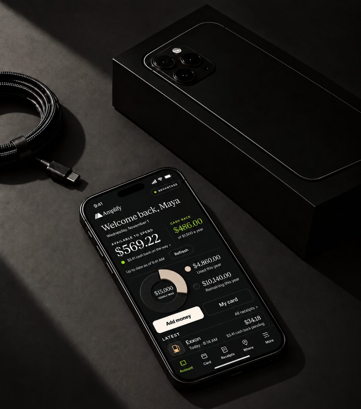 A phone showing the Amplify app beside its box and a charging cable on a black surface